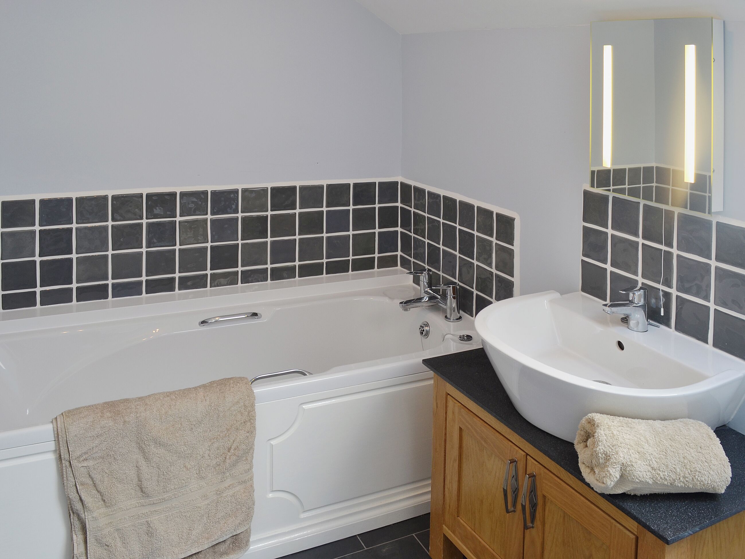 A bathroom with a bathtub, a sink, and a mirror.