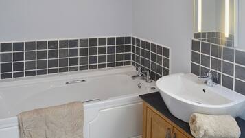 A bathroom with a bathtub, a sink, and a mirror.