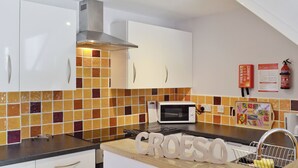 Une cuisine moderne avec des armoires blanches, une hotte de cuisinière en acier inoxydable, un four à micro-ondes et un pare-feu en carreaux.