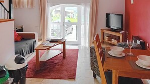 Un salon avec un canapé, une table à manger et des chaises, un téléviseur et un mur rouge.