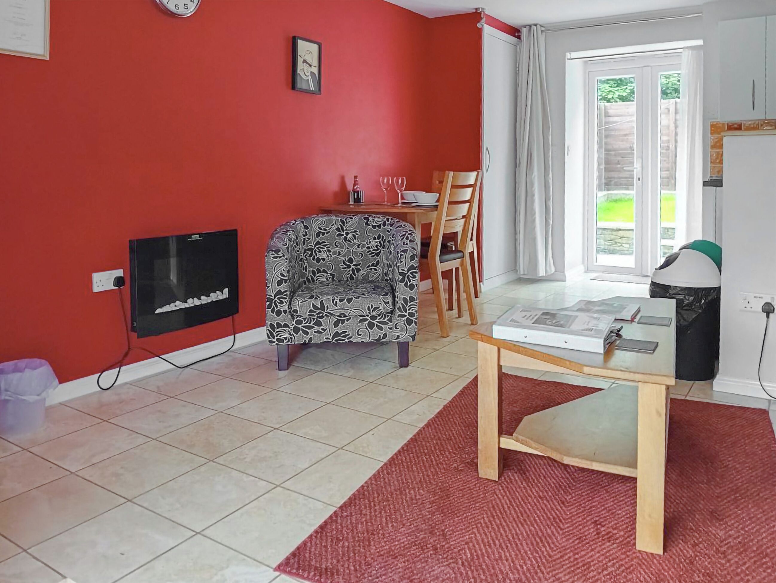 A living room with a red wall, a patterned sofa, a wooden table, and a television.