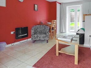 A living room with a red wall, a patterned sofa, a wooden table, and a television.
