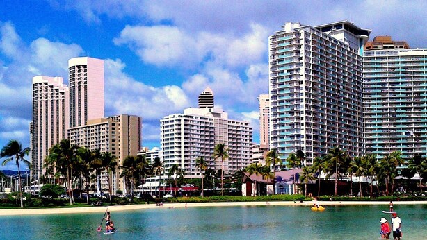 A beachfront hotel with multiple high-rise buildings, palm trees, and a clear sky. - Ilikai Hotel Condo Vacations (Honolulu)