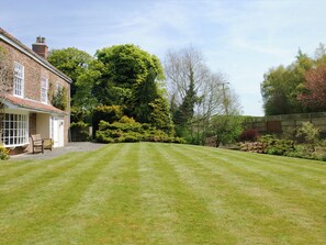 A well-maintained lawn in front of a brick house with a wooden bench and a small garden area. - Greenlands Farmhouse (Barmby Moor, York)