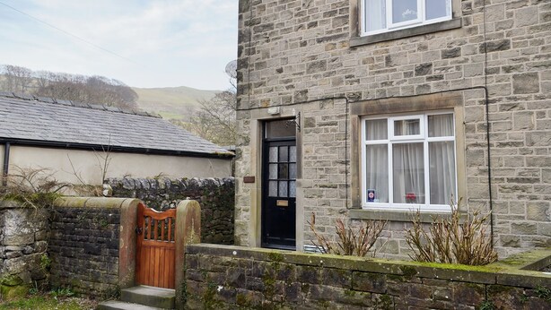 A stone house with a black door, a window with curtains, and a satellite dish.