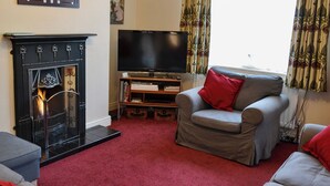 A living room with a fireplace, a television, a sofa, and a red carpet.