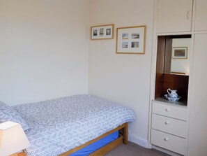 Quarto com cama, penteadeira, espelho e quadros na parede.