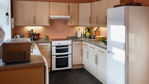 A kitchen with wooden cabinets, a stove, oven, and a refrigerator.