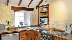 Una cocina con armarios de madera, un lavavajillas Bosch, un horno Bosch, un fregadero y un ventanal con vistas al exterior.