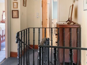 Eine Treppe mit aufwendig gestalteten schwarzen Geländern, einer Holztür und einem Spiegel auf einem Holzkabinett.