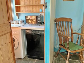 Une cuisine compacte équipée d’un lave-linge, d’un lave-vaisselle et d’un four à micro-ondes posé sur le plan de travail.