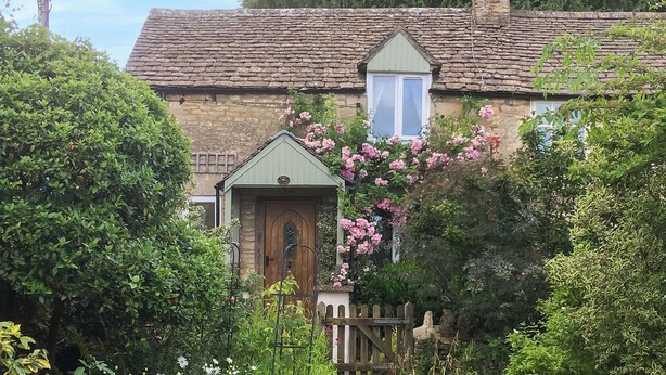 Une charmante maison de campagne avec une façade en pierre, une porte en bois et un petit porche.