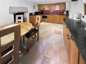 A kitchen with wooden cabinets, a black countertop, and a tiled backsplash.