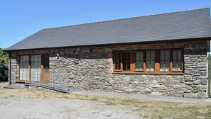 Un bâtiment en pierre doté d’un toit en pente et de grandes fenêtres.