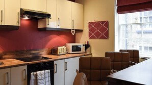 A modern kitchen with white cabinets, a microwave, a toaster, and a wooden countertop. There is a window with a view of buildings outside. - 2 bedroom accommodation in Whitby (Whitby)