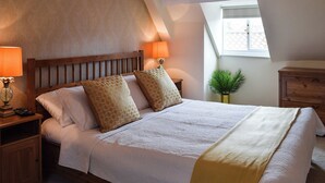 A neatly made bed with a wooden headboard, two bedside lamps, and a small potted plant. - 2 bedroom accommodation in Whitby (Whitby)