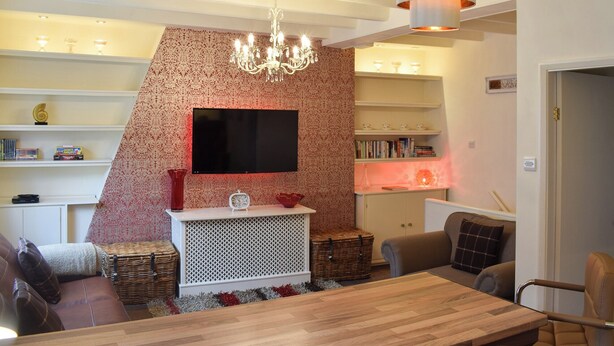 A modern living room with a fireplace, a television, and a dining area. - 2 bedroom accommodation in Whitby (Whitby)