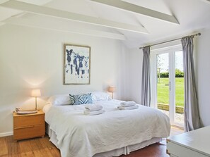 Ein Schlafzimmer mit einem Bett, zwei Nachttischen, einem Fenster mit Vorhängen und einem Bild an der Wand.