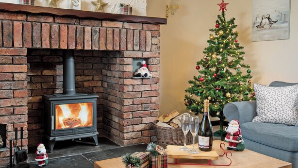 A cozy living room with a brick fireplace, a decorated Christmas tree, and a sofa. - 3 bedroom accommodation in Dunstan, near Craster (Dunstan, near Craster)