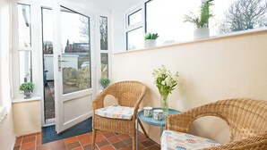A small balcony with wicker chairs, a table, and potted plants. - 3 bedroom accommodation in Dunstan, near Craster (Dunstan, near Craster)