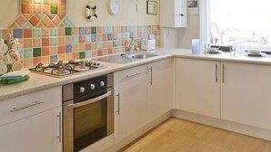 Una cocina con estufa a gas, horno y salpicadero de azulejos.