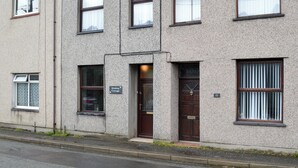 Ein zweistöckiges Gebäude mit einem Schild, das es als Ferienhaus kennzeichnet. Es gibt mehrere Fenster, eine Tür mit Klingel und ein kleines Schild darüber.