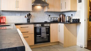 Eine moderne Küche mit hellen Holzschränken, einem schwarzen Backofen und einer Edelstahl-Dunstabzugshaube.