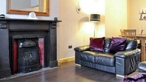 Ein Wohnzimmer mit Kamin, einer Ledersofa, einem Tisch und einer Lampe.