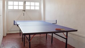 Een tafeltennistafel in een ruimte met een witte deur en houten balken in het plafond.