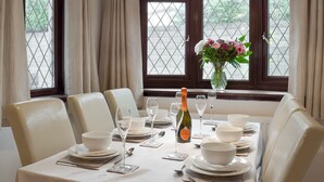 Een eetzaal met een tafel gedekt voor zes personen, inclusief wijnglazen, borden en een fles champagne.