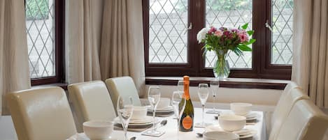 A dining room with a table set for six, including wine glasses, plates, and a bottle of champagne.