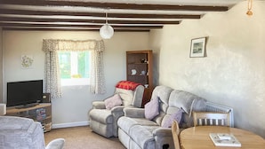 Ein gemütliches Wohnzimmer mit grauem Sofa, einem Holztisch und einem Fernseher.