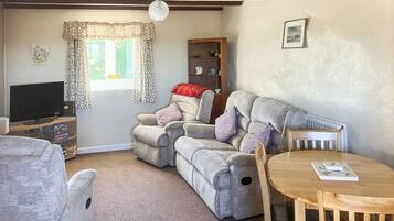 A cozy living room with a grey sofa, a wooden table, and a television.