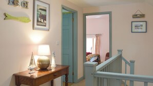 A hallway with a wooden console table, a framed poster, and a sign reading "Beach Huts". - 3 bedroom accommodation in Llanybri, near Carmarthen (Llanybri, near Carmarthen)