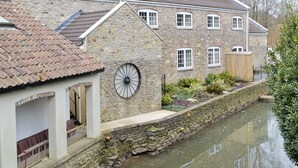 A stone building with a tiled roof, a water channel, and a wooden fence. - 2 bedroom accommodation in Spring Gardens, Frome (Spring Gardens, Frome)