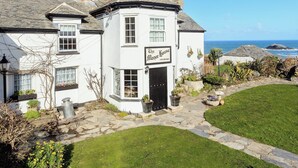 A white building with a sign reading "The Manor House 19th Century" and a view of the sea in the background. - 7 bedroom accommodation in West Pentire (West Pentire)