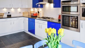 Una cocina moderna con gabinetes blancos y azules, una estufa a gas y electrodomésticos de acero inoxidable.