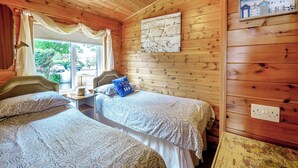 Une pièce chaleureuse aux murs en bois et dotée d’un lit recouvert d’une literie à motifs.