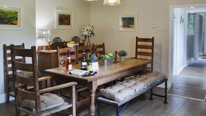 A dining area with a wooden table, chairs, a bench, and a hanging light fixture.