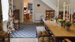 A dining area with a wooden table, chairs, and a staircase leading to another room.