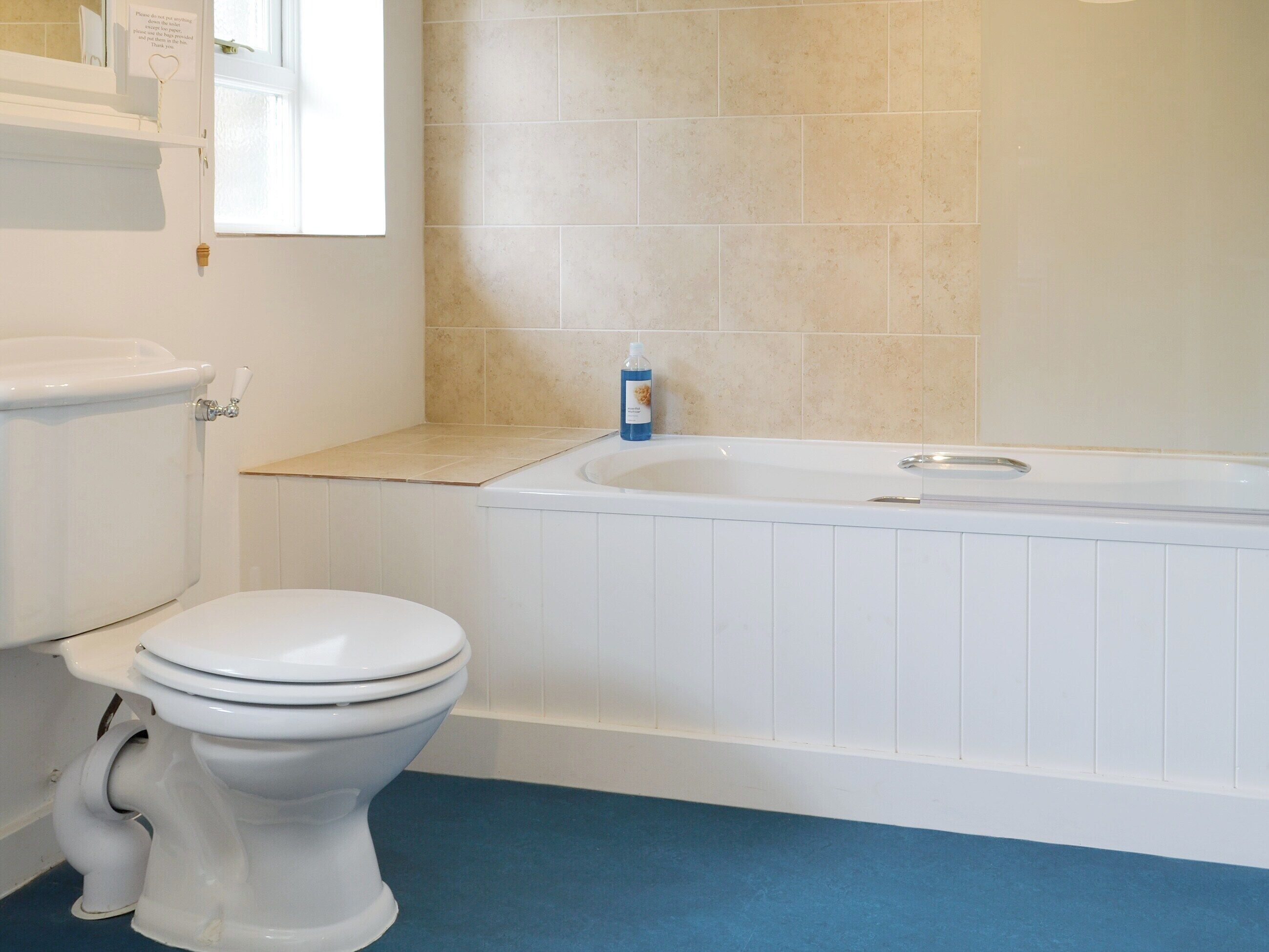 A bathroom with a toilet, a bathtub, and a window.