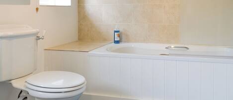 A bathroom with a toilet, a bathtub, and a window.