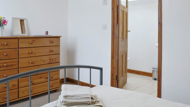 A bedroom with a wooden dresser, a metal bed frame, and a skylight. - 2 bedroom accommodation in Tregarth, near Bangor (Tregarth, near Bangor)