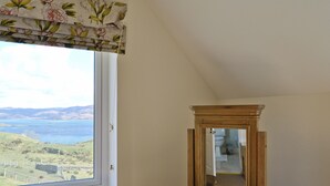 Une pièce avec une fenêtre donnant sur un paysage, une commode en bois et un miroir.