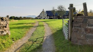 Une propriété située en zone rurale, avec un chemin de gravier menant à une maison, un mur de pierres et un panneau indiquant « PROPRIÉTÉ PRIVÉE ».