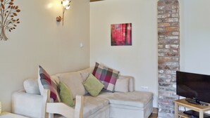 Una sala de estar acogedora con un sofá blanco, un mueble para televisor y una chimenea.