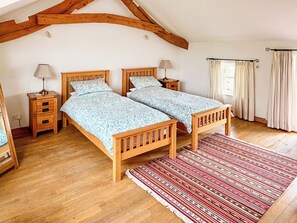 A bedroom with two wooden beds, a red patterned rug, wooden nightstands, and a window with curtains. - 3 bedroom accommodation in Sockbridge, near Ullswater (Sockbridge, near Ullswater)