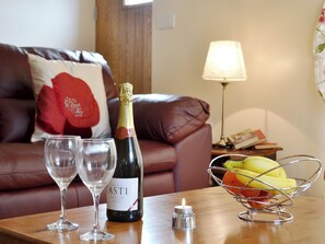 A bottle of ASTI wine, two wine glasses, a candle, and a fruit bowl on a wooden table in a living room. - 1 bedroom accommodation in Carmarthen (Carmarthen)