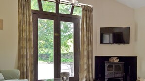 Een woonkamer met een glazen salontafel, een bank, een open haard en een aan de muur bevestigde televisie.