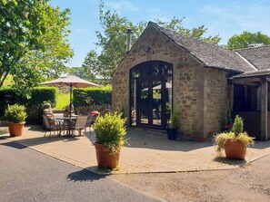 A stone building with a large glass door, outdoor seating, and potted plants. - 2 bedroom accommodation in Lumsdale, Tansley Wood, near Matlock (Lumsdale, Tansley Wood, near Matlock)